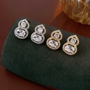 Wu Lou gourd earrings in gold and silver finish with sparkling cubic zirconia inlay
