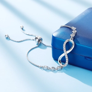 Detail of silver infinity bracelet with small diamonds on blue jewelry box background