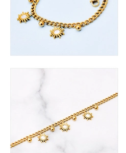 Detail of gold chain bracelet with sunflower shell pendant and metal beads on marble