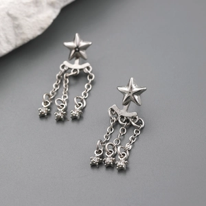 Boucles d'oreilles étoiles argentées avec pendentifs à pompons et détails en zircon