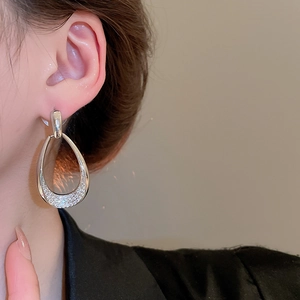 Close-up of elegant silver teardrop earrings with pavé zircons worn by a model