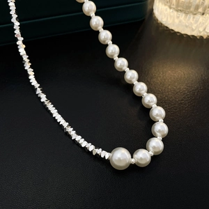 Close-up of elegant pearl and geometric silver bead splice necklace on black leather