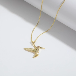 Detailed close-up of a gold hummingbird pendant necklace with sparkling white crystals