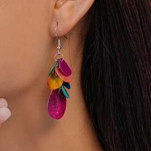 Gros plan d'un mannequin portant des boucles d'oreilles en perles de coquillage colorées