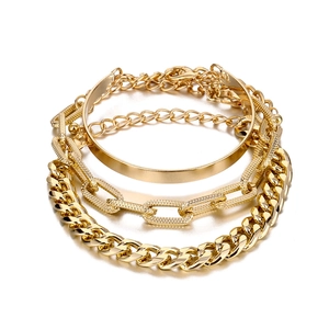 Polished gold multi-layer bracelet set with smooth bangle and chains on white background