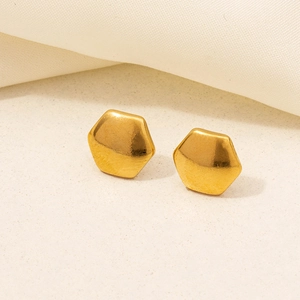 Close-up of golden hexagonal stud earrings with a polished metallic mirror finish