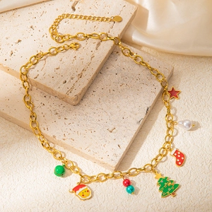 Golden stainless steel Christmas necklace featuring festive enamel charms on stone surface