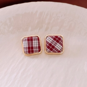 Détail de boucles d'oreilles carrées en tissu à carreaux rouge et blanc avec bord doré
