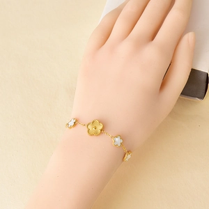 Golden flower charm bracelet with white shell inlays on wrist for romantic style