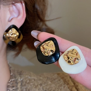 Close-up of geometric acetate leopard earrings with 18k gold-plated hammered metal centers