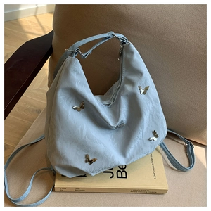 Detail of light blue wrinkled nylon crossbody bag with silver butterfly metal charms