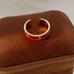 Detailed macro view of 18k gold plated open ring with red enamel and floral patterns