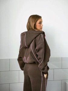 Détail du dos du sweat à capuche marron avec liseré rose et broderie du logo M épuré
