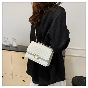 Detail of white V-quilted faux leather bag with elegant gold chain and turn-lock closure
