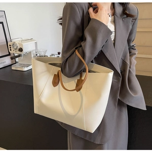 Minimalist beige tote bag with brown straps styled on a grey blazer for a chic look