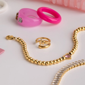 Gros plan de la bague étoile dorée et des bagues en résine rose sur surface blanche