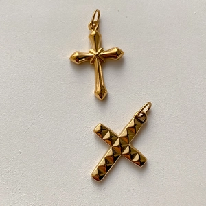 Dettaglio macro di ciondoli a croce placcati in oro con motivi gotici e a rombi