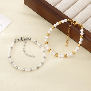 Detail of beaded pearl bracelets with gold and silver accents on textured fabric