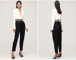 Detail of white cropped blazer with silver fringe tassels and black tailored trousers