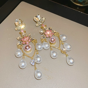 Detailed macro view of crystal flower earrings with white water-drop pearls