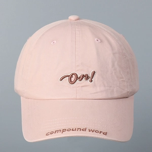 Primer plano de gorra de béisbol rosa con bordado de letras en el frente y visera