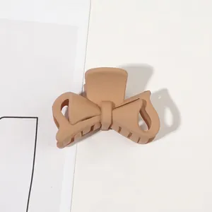 Detailed top view of a matte nude bow-shaped hair claw clip on a clean white surface