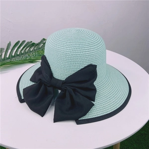 Détail d'un chapeau de paille vert menthe avec grand nœud noir et bordure élégante