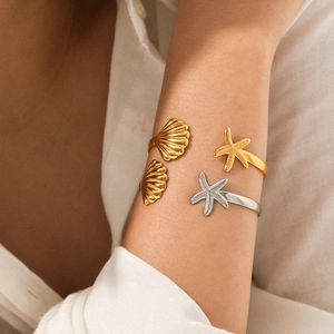 Close-up of model wearing adjustable starfish and shell bracelets in gold and silver finish