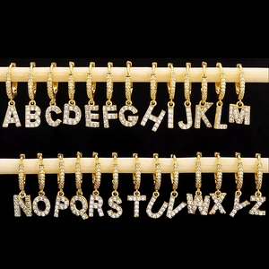 Macro display of 26 gold-plated initial earrings with zircon inlays on wooden beams