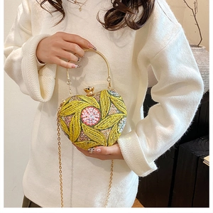Close-up of heart-shaped evening bag with sequin floral embroidery and gold ring handle