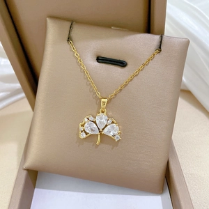 Detailed macro view of golden ginkgo leaf necklace with sparkling rhinestones on jewelry box