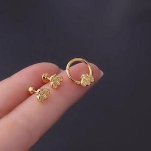 Golden bee stainless steel cartilage piercings set displayed on a fingertip