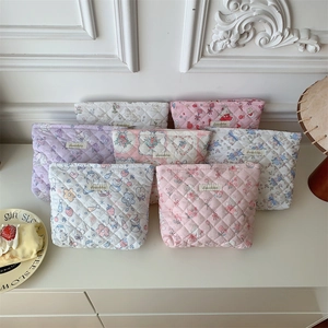 Quilted cosmetic bags in pastel colors with floral and cartoon prints on a vanity desk