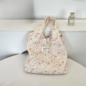 Detail of quilted tote bag featuring colorful bear patterns and branded fabric label