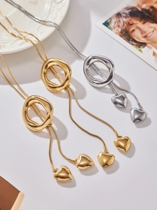 Detailed macro view of liquid metal gold and silver heart pendants on a snake chain necklace