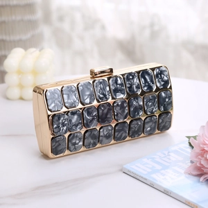 Detail of acrylic evening clutch with marble texture blocks and gold metal frame