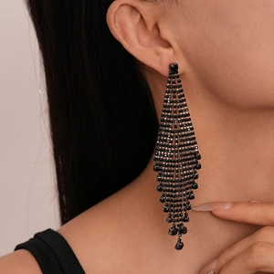 Close-up of black long tassel earrings with sparkling rhinestones worn by a model