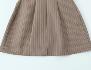 Detailed view of brown vertical pinstripe fabric with pleated hem and knitted texture