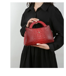 Close-up of red crocodile-embossed handbag with golden V-shaped metal decoration