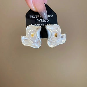 Macro shot of 925 silver camellia flower earrings with gold center on display card