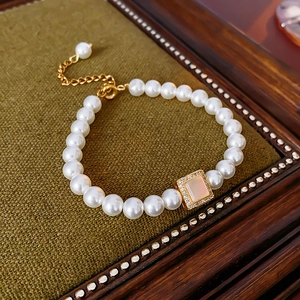 Detail of 18k gold plated bracelet with pearls and a square inlaid pink shell charm