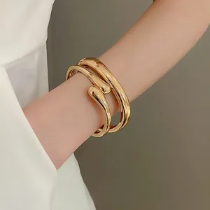 Minimalist gold plated wrap bracelet featuring a polished mirror finish on model