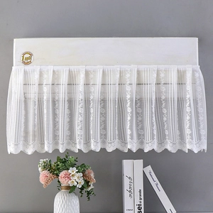 Detail of white lace cabinet curtain with floral embroidery and elegant wavy edges