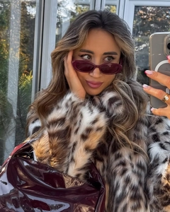 Détail d'un manteau léopard en fausse fourrure avec lunettes bordeaux et sac brillant