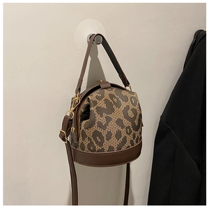 Detail of a brown leather and leopard print bucket bag with gold hardware accents