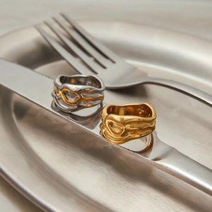 Artistic display of irregular lava style 18K gold rings on metal cutlery and plate