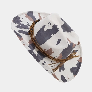 Detail of western cow print hat with braided cord and wooden beads trim on white felt