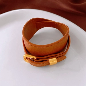 Close-up of double-wrap brown leather choker with gold metal buckle and stitching
