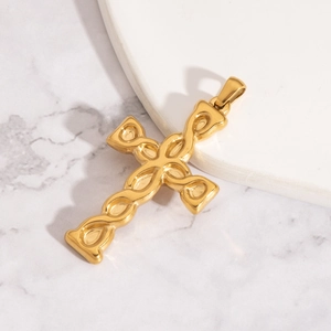 Détail d'un pendentif croix dorée avec motif tressé sur fond en marbre blanc