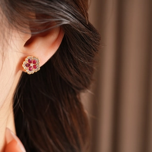 Close-up of elegant flower stud earring with red gemstones and crystals on model